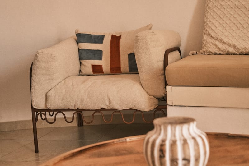 Reading corner inside the tower with a linen-cushioned daybed, woven mirror, and round wooden coffee table.
